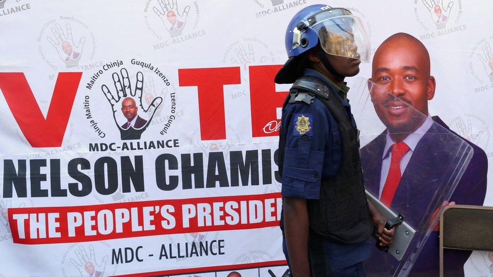 A riot police officer in front of an MDC Alliance poster in Harare, Zimbabwe