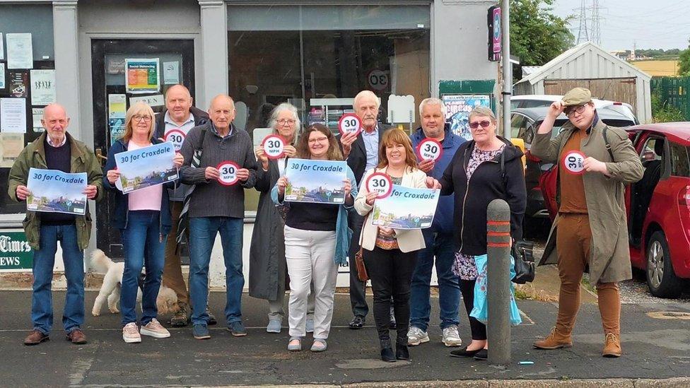 Residents hold 30mph speed limit signs up in protest