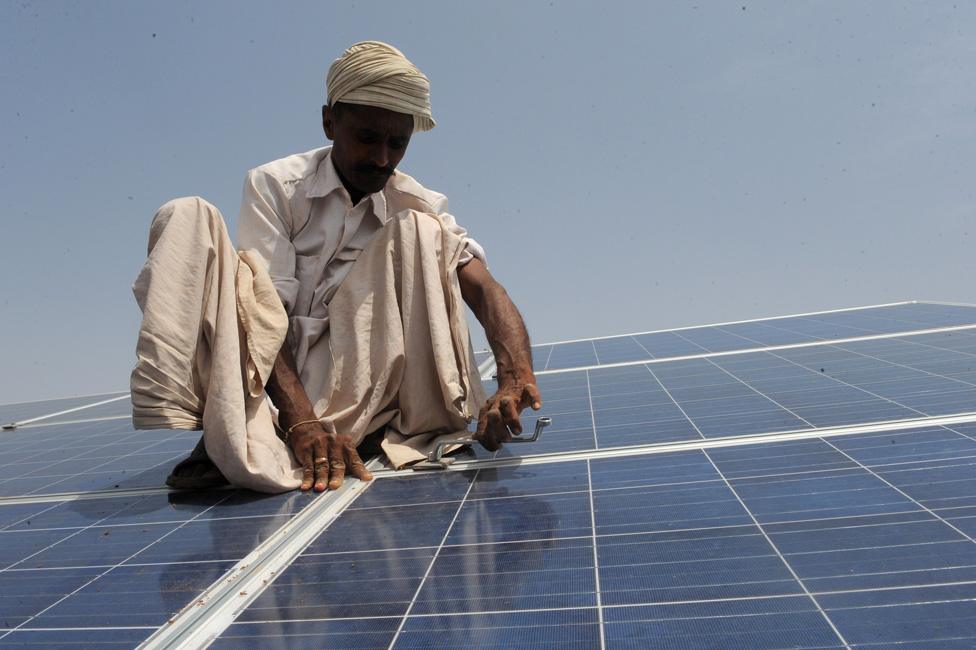 A worker installs solar panels at the Gujarat solar park in Patan, India