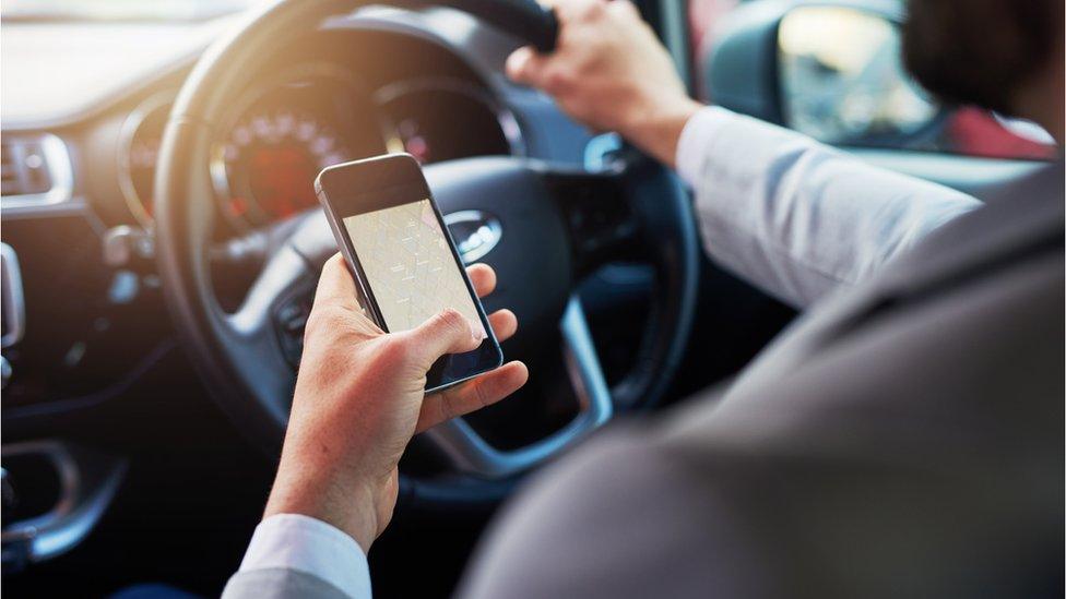 Man using mobile phone at wheel of car