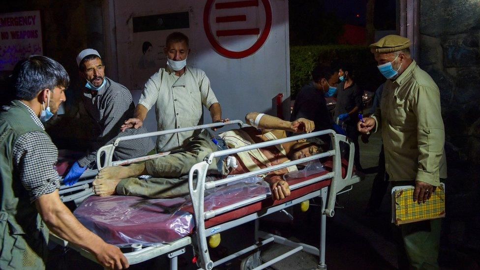 Hospital staff bring an injured man for treatment after the Kabul airport attack