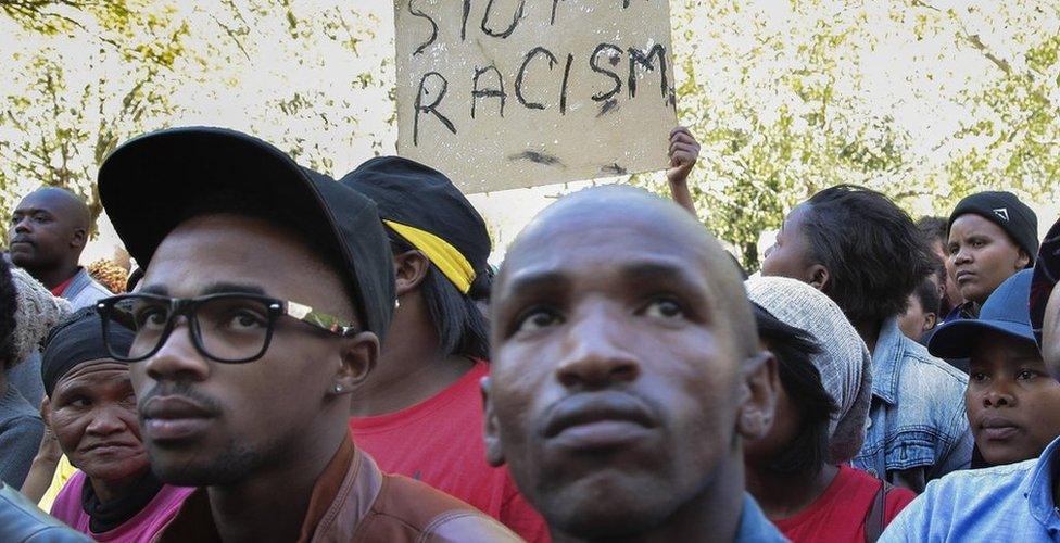 Protesters in South Africa hold up a "stop racism" sign