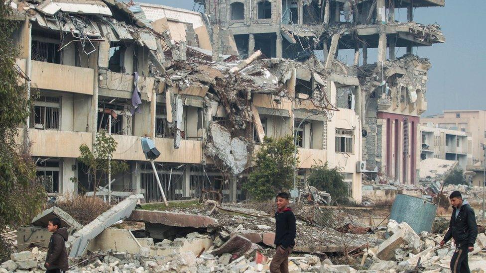 Iraqi boys walk near the University of Mosul after its liberation from the Islamic state group (IS) control, during the ongoing military operation against the jihadists, on January 21, 2017