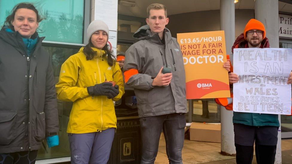 Doctors on strike holding up placards about their pay