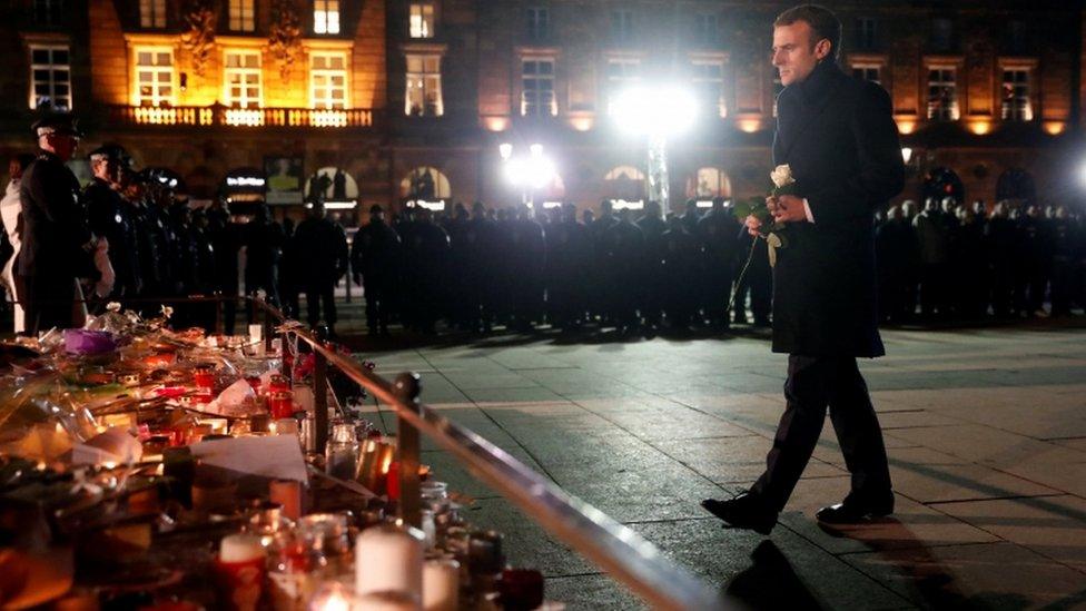 The French president lays a flower at a monument for the victims in Strasbourg