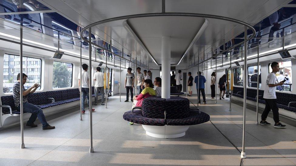 People try the Transit Elevated Bus TEB-1 as they conduct a test run after it was unveiled in Qinhuangdao, north China's Hebei Province