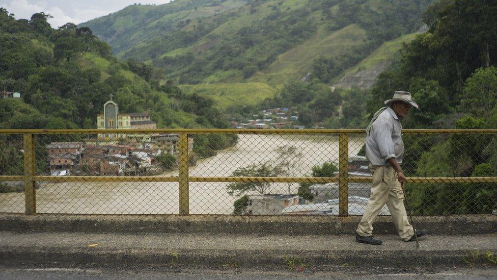 A man walks over a bridge over the river Cauca