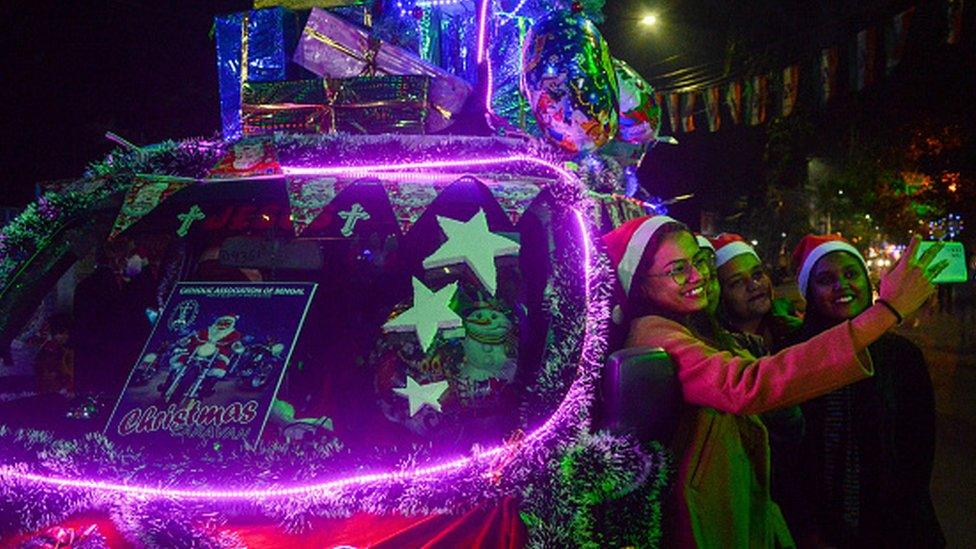 Girls are seen taking selfie with a Christmas carol van at a street in Kolkata , India , on 21 December 2021