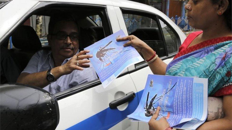 An Indian health worker distributes leaflets on a street in an awareness drive against the spread of dengue fever, a mosquito borne disease, in Kolkata, India,