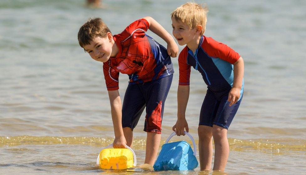 Hamish and William fill their buckets with water at the beach on July 17, 2021 in Weymouth