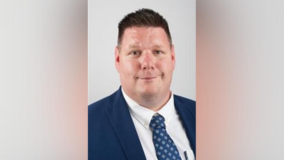 Nick Housden wearing a blue suit and blue tie with spots on it