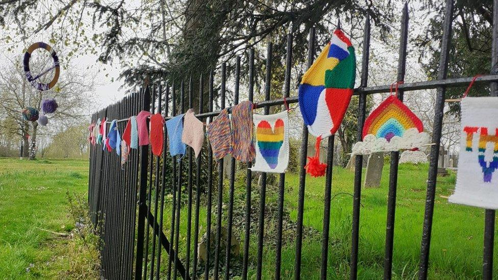 Yarn bombing along metal fence.