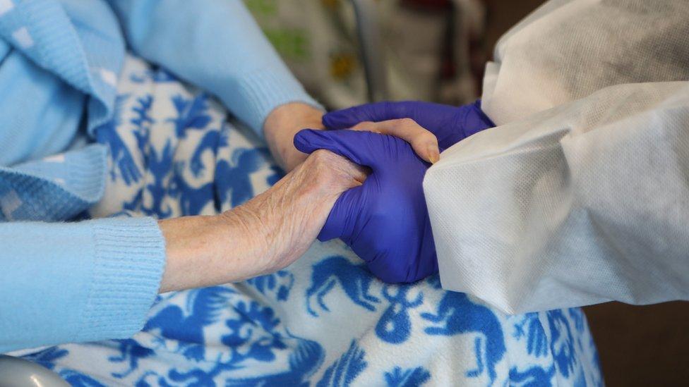 Care worker holding hands of elderly woman