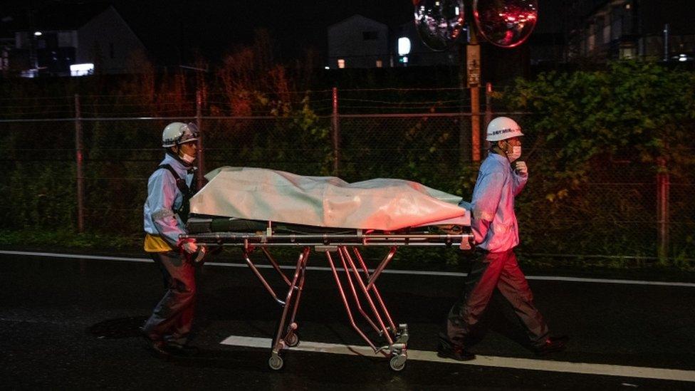 Emergency crew wheel a stretcher away from the building