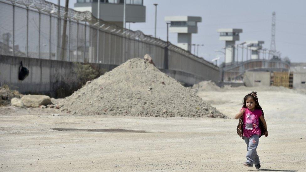 A girl walks along the perimeter wall of the El Altiplano prison, where Mexican drug lord Joaquin "El Chapo" Guzman is being held, on February 24, 2016 in Almoloya de Juarez, Mexico. AFP