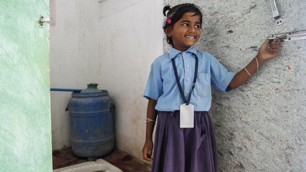 A girl in India stands outside a toilet fitted by WaterAid