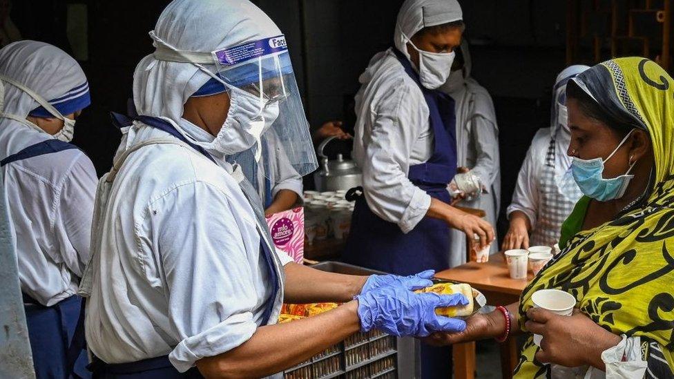 Members of The Missionaries of Charity distribute food to underprivileged people