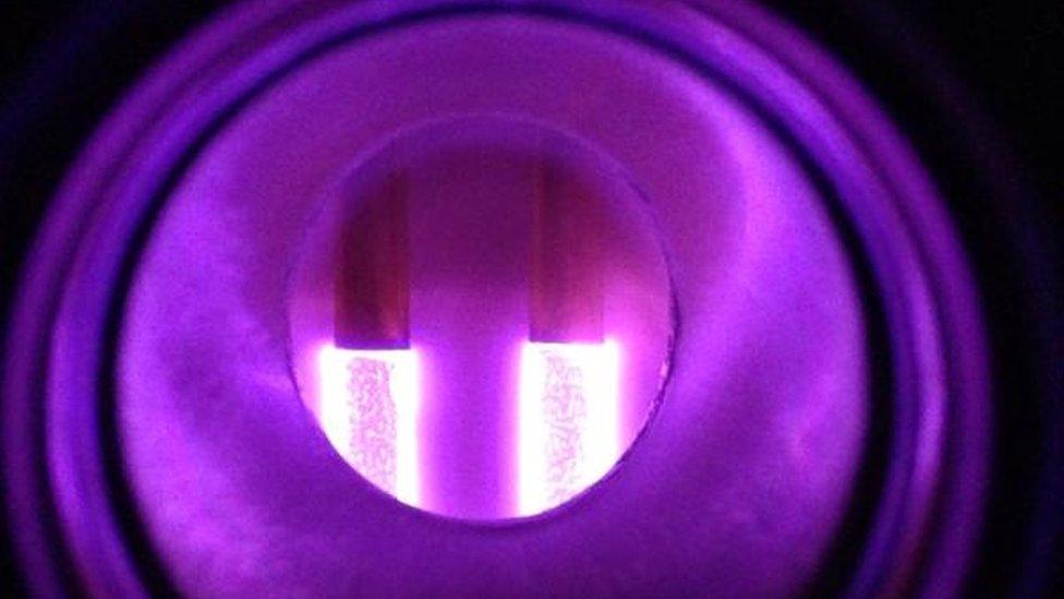 Two glowing plasma rods in an isolation chamber creating a purple glow