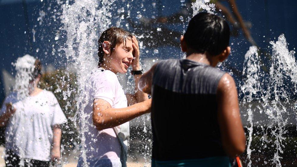 Children play in a fountain to escape the heat at the Australian Open tennis tournament in Melbourne