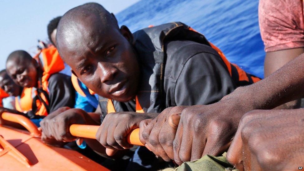 Migrants sit on a Norwegian Coast Guard boat after being transferred from the Italian Navy Ship Fulgosi during a migrant search and rescue mission off the Libyan Coasts, Tuesday, Sept. 1, 2015