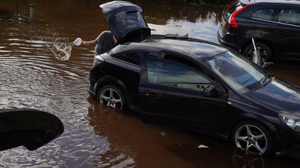 Resident in Rothbury in Northumberland bails water from their vehicle after the River Coquet burst its banks