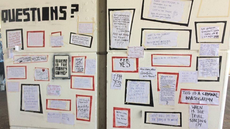 Wall of posters reading 'questions', 'where is the money going?' 'how many other Grenfell's are there?'