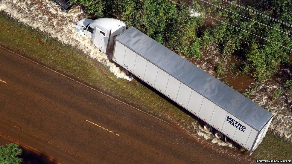 A white lorry on its side in floodwaters