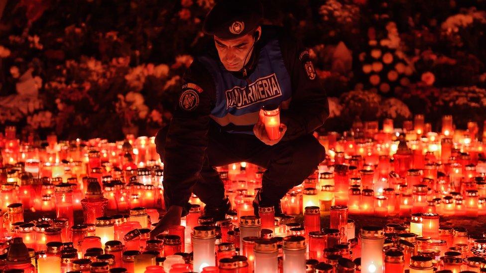 A policeman lights a candle in memory of those who died at the Colectiv nightclub