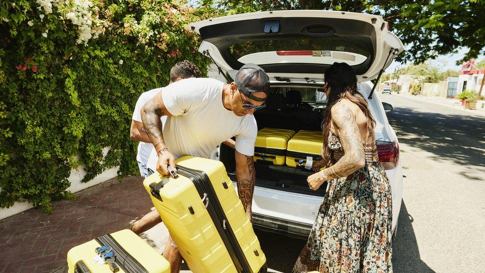 People putting luggage in a hire car