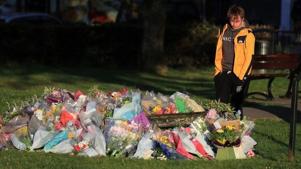 Patrick James, the son of PCSO Julia James, looks at floral tributes left near her family home in Snowdown