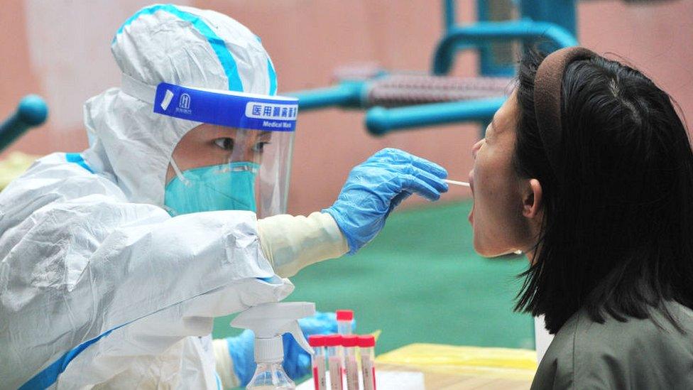 A medical worker collects a Covid-19 swab sample from a resident in Shanghai.