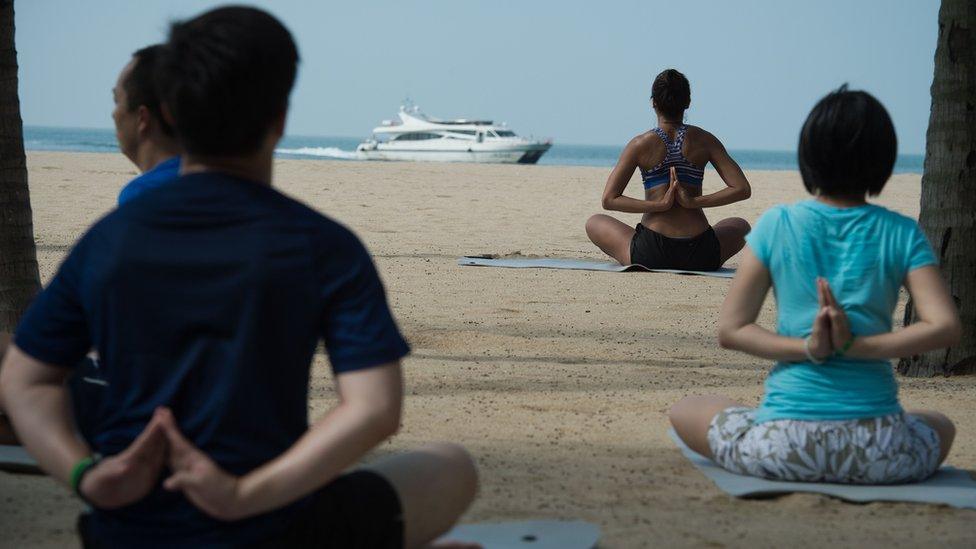 People doing yoga on the beach