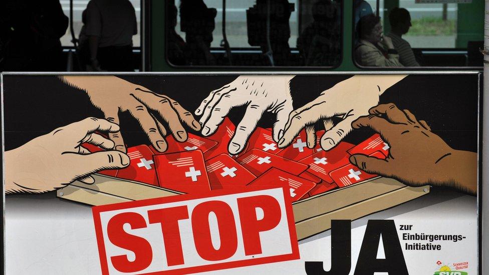 This file picture taken on 26 May 2008 in Basel shows commuters taking the tramway behind a poster of the hard right Swiss People's Party depicting multi-coloured hands grabbing Swiss passports