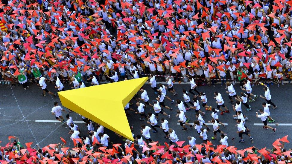 Demonstrators hold a giant yellow cursor as they gather on Meridiana street as they wave "Estelada" flags (pro-independence Catalan flags)