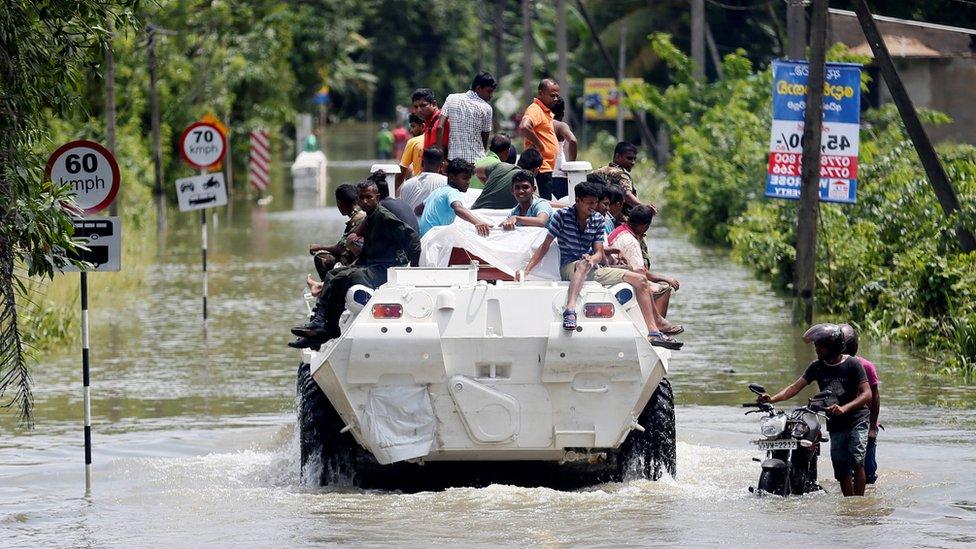 People are transported on top of an armoured personnel carrier on a flooded road in Sri Lanka