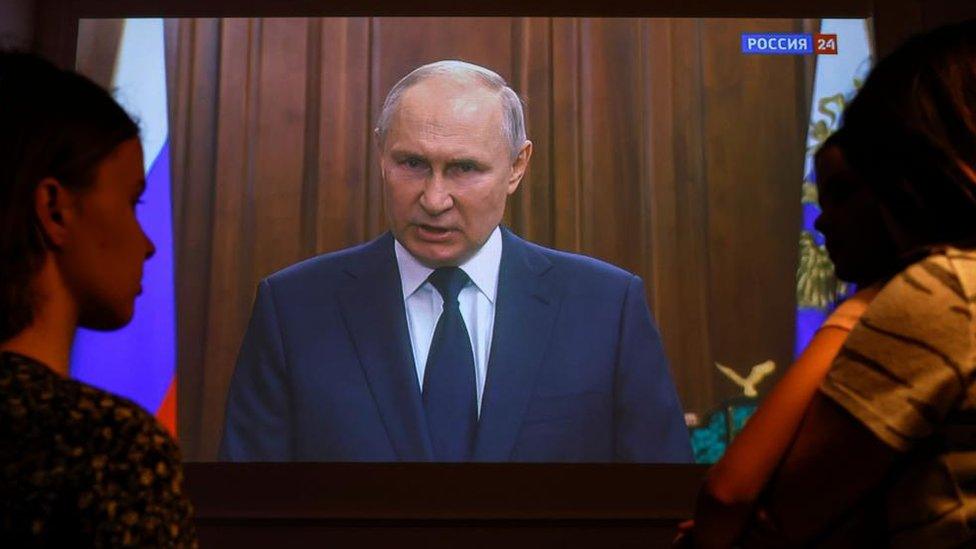 A family watches Russian President Vladimir Putin's video address to the Nation in Moscow, Russia