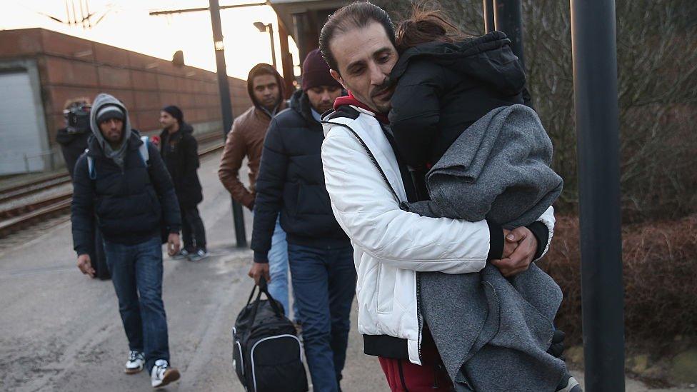 Migrants walk to police vans after police found them while checking the identity papers of passengers on a train arriving from Germany on 6 January 2016 in Padborg, Denmark