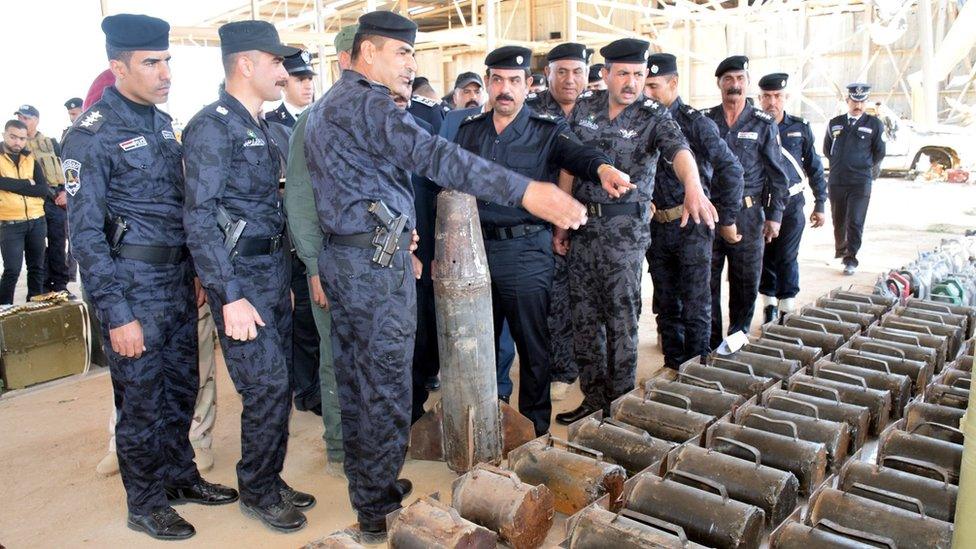 Iraqi police officers inspect weapons and bombs seized during military operations in Ramadi (16 February 2016)