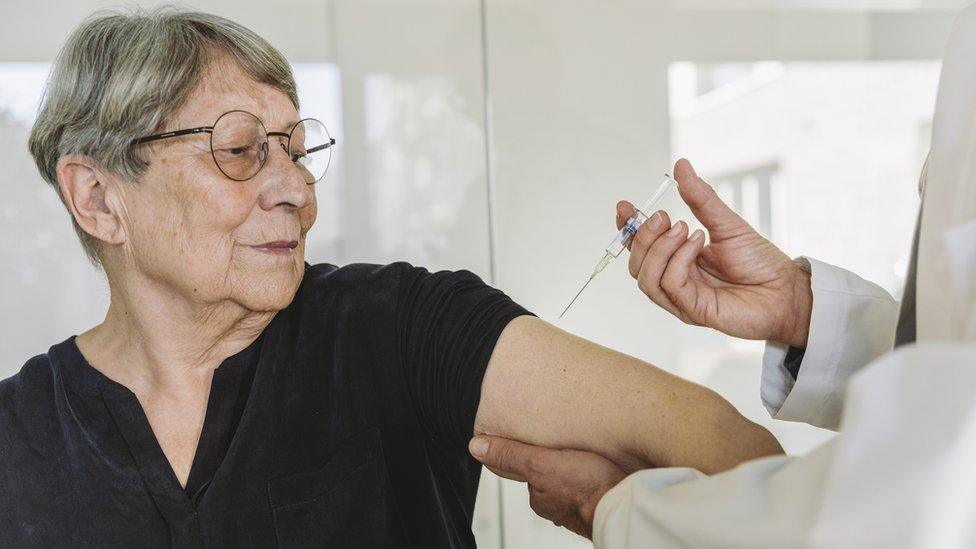 Doctor injecting vaccine into senior patient's arm