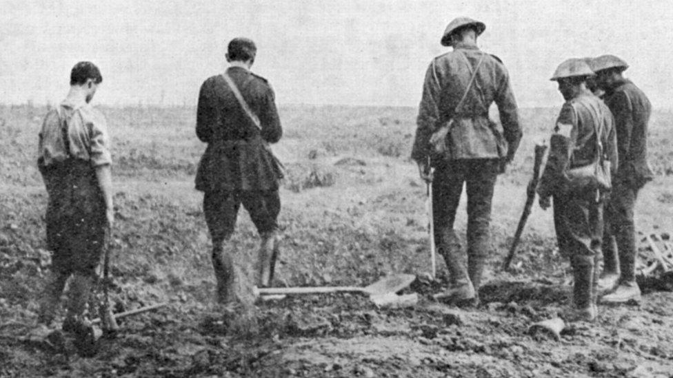 WWI Army chaplain conducting burial service in the field while a burial party stands by 1916