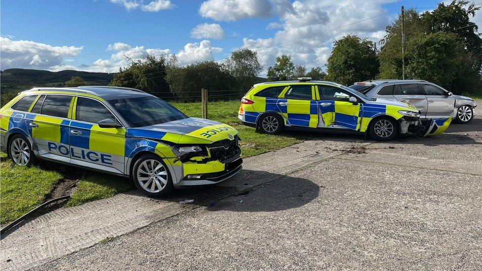 Three police cars showing damage after being rammed by tractor