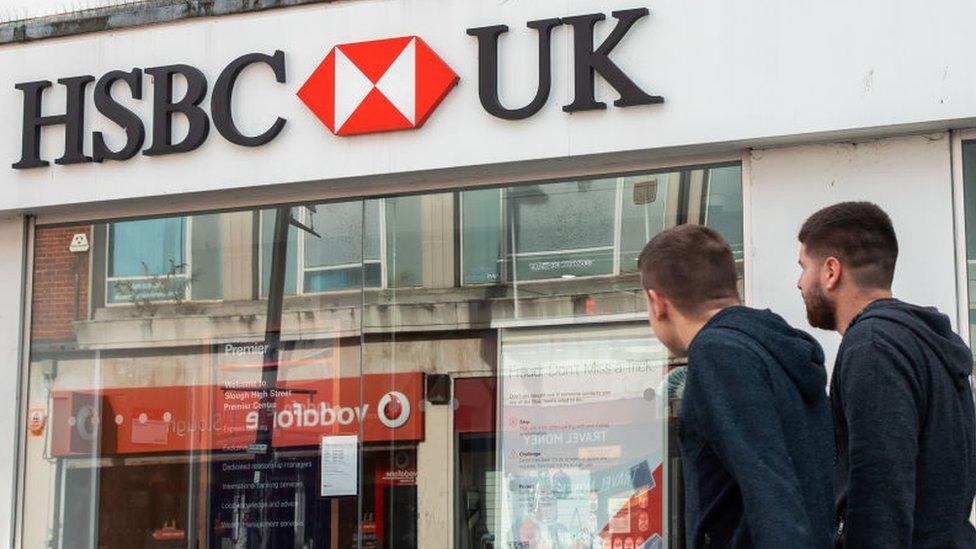 Two people walk past a HSBC branch in Slough, UK.