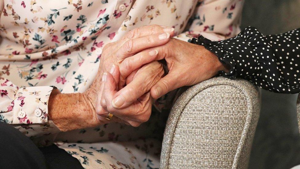 Two people holding hands on armchairs