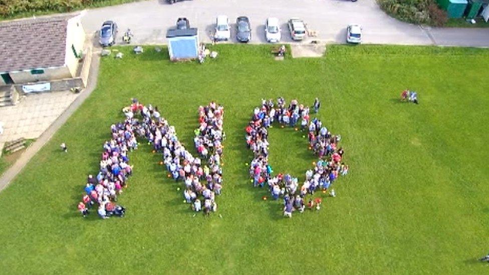 Protestors spell out the word "no"