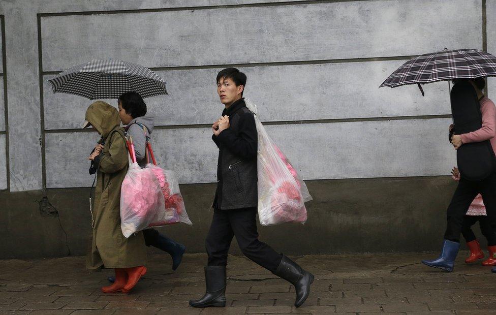 North Koreans carry bouquets of decorative flowers as they make their way towards the Kim Il Sung Square on Friday, 6 May 2016, in Pyongyang, North Korea