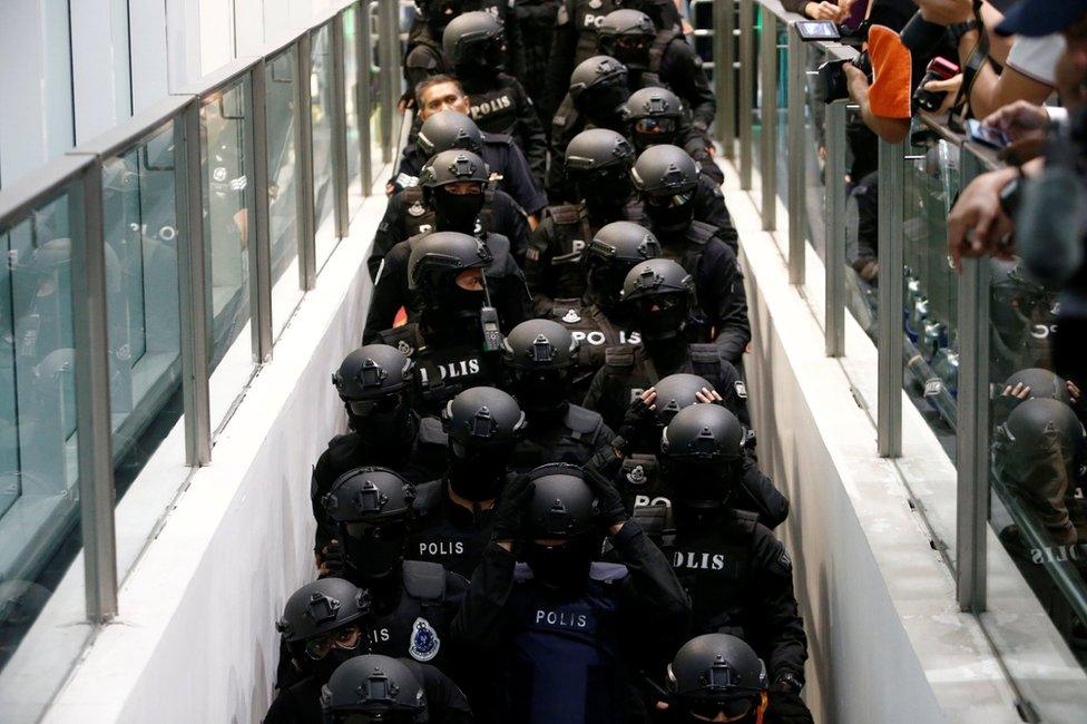 Armed policemen take the escalator as they escort Indonesian Siti Aisyah and Vietnamese Doan Thi Huong, who are on trial for the killing of Kim Jong Nam, the estranged half-brother of North Korea"s leader, at the Kuala Lumpur International Airport 2 in Sepang, Malaysia 24 October, 2017.