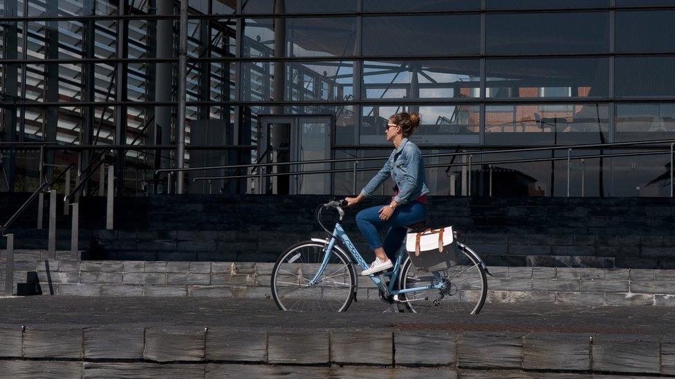 Woman riding bike past the Senedd