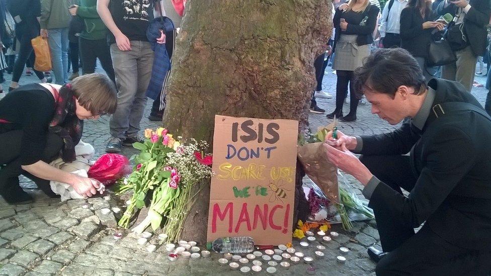 Laying flowers and lighting candles at a vigil in May 2017