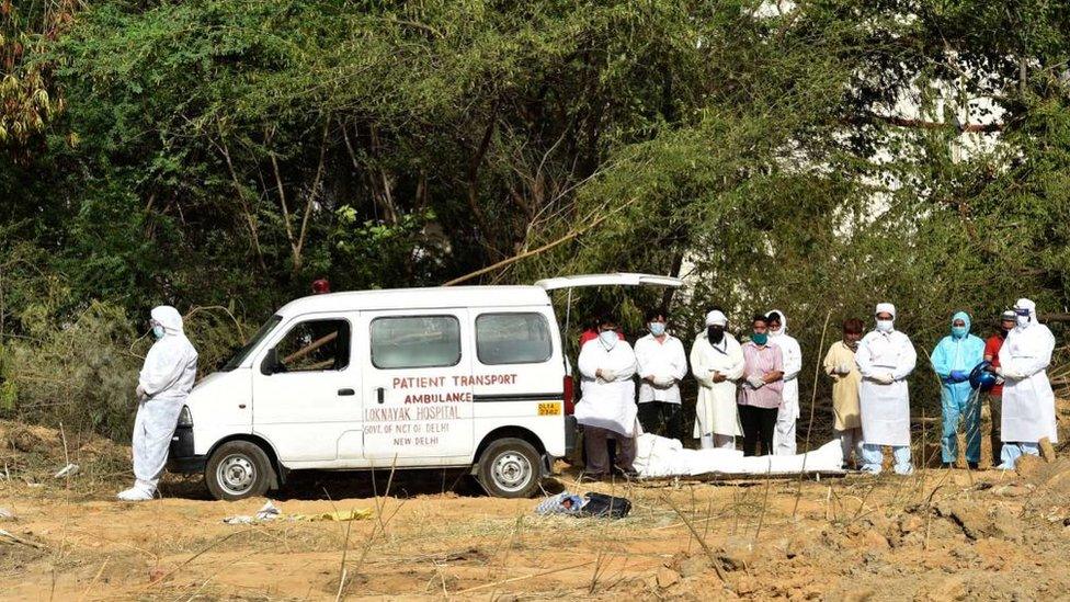 Health workers in PPE suits and family members perform funeral prayers before the burial of a coronavirus disease in Delhi.