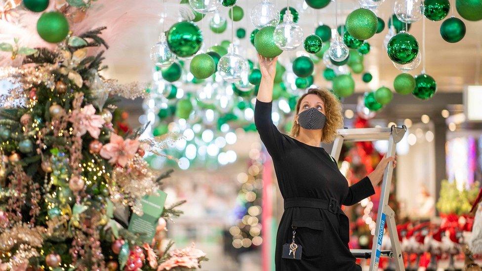 Shop worker hangs Christmas decorations